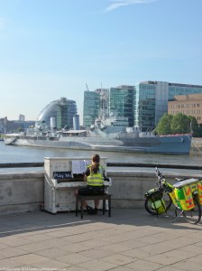Paramedic playing piano overlooking HMS Belfast