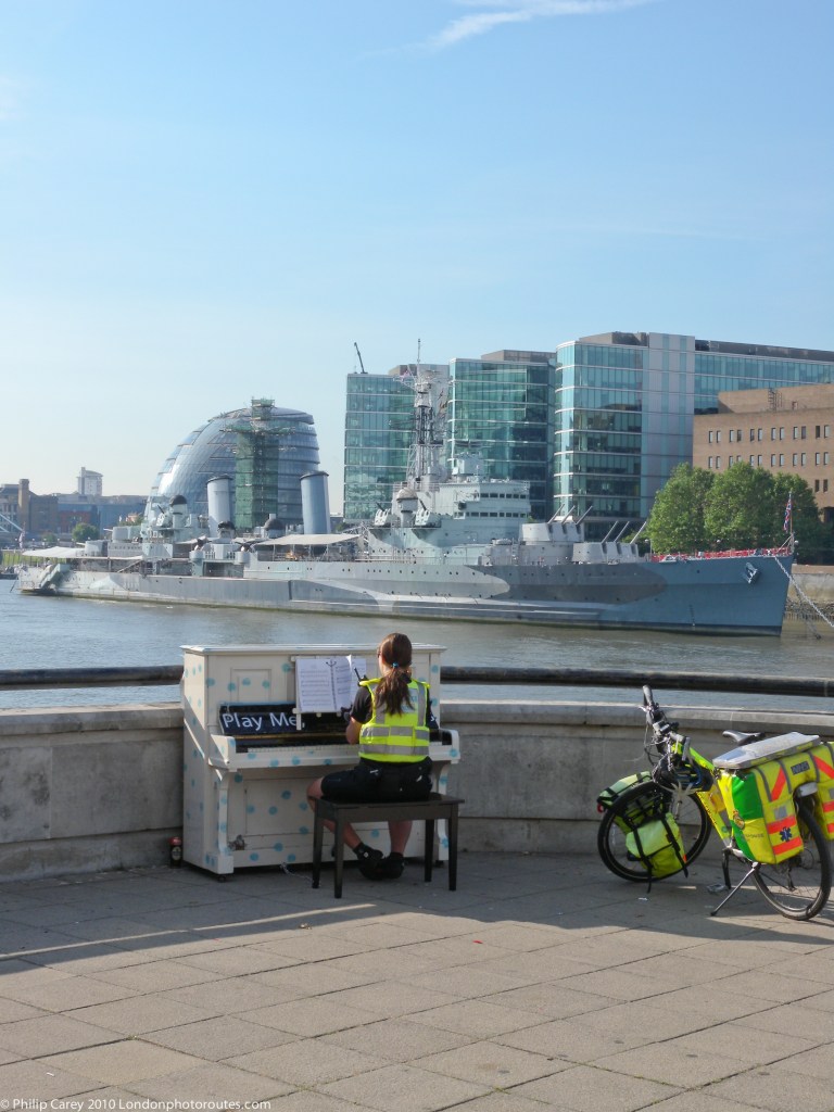 Paramedic playing piano overlooking HMS Belfast